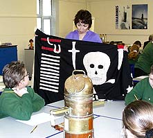 The museum's Education Officer showing pupils a Jolly Roger flag